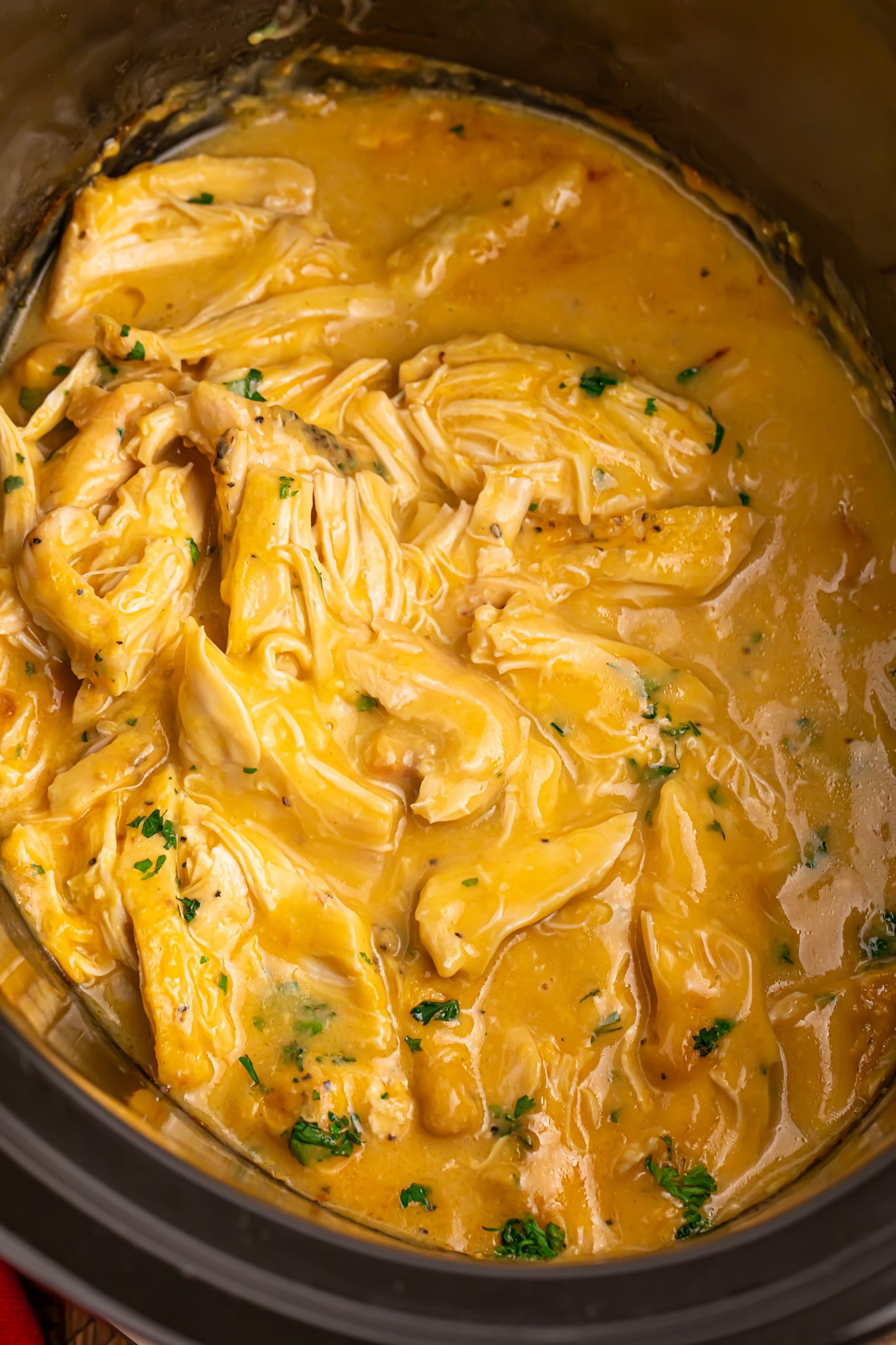 overhead look of shredded chicken and gravy in a slow cooker
