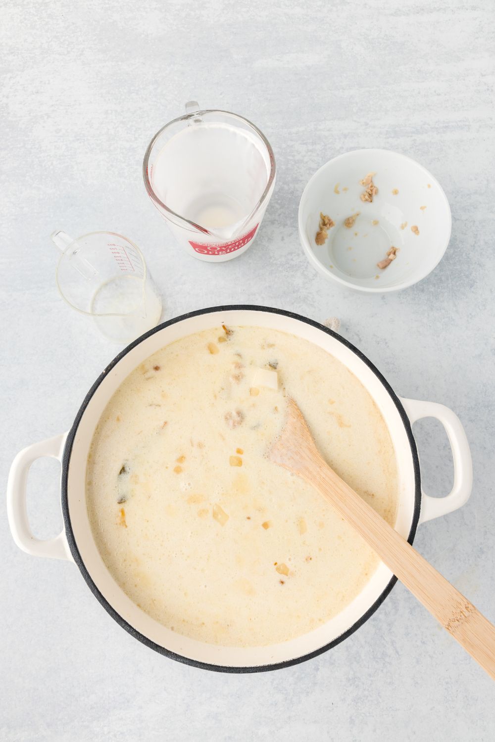 stirring the heavy cream into the pot of New England Clam Chowder