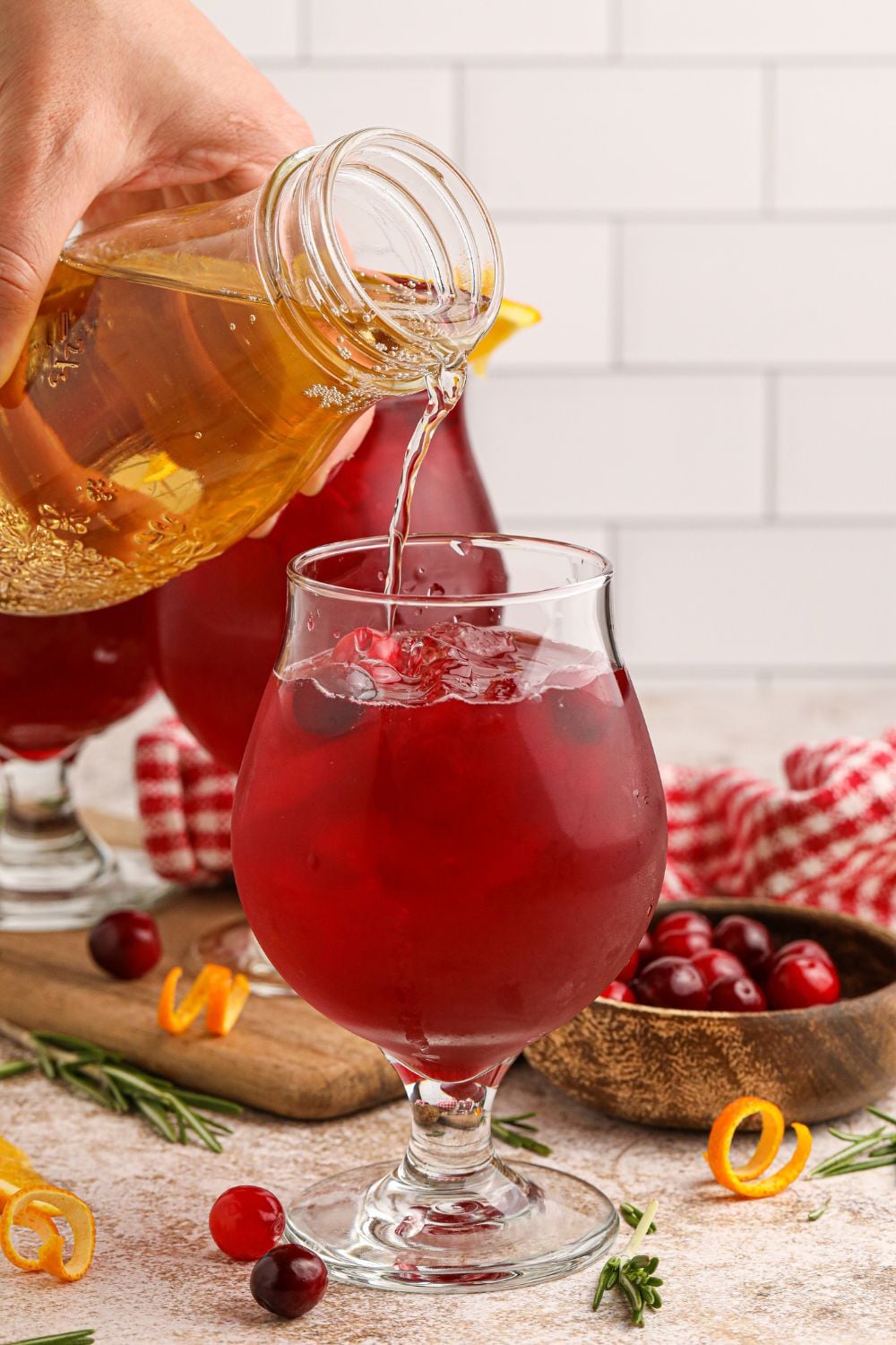 pouring juice into a glass for making a cranberry cocktail