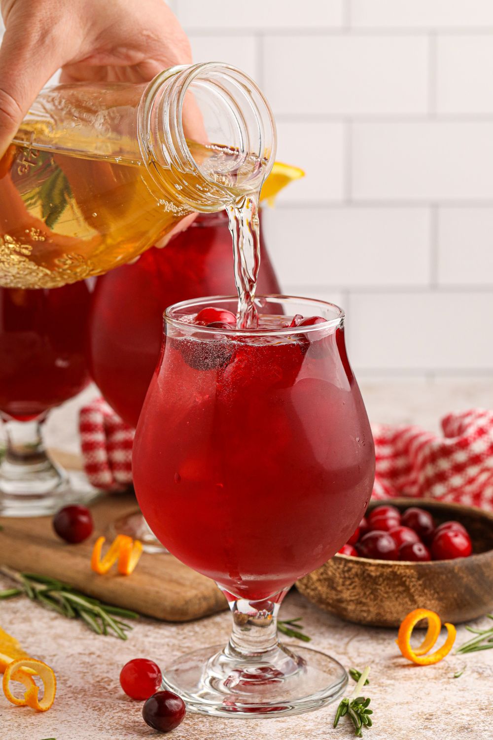 Cranberry Whiskey Sour on table with some juice being poured in the glass to top it off 
