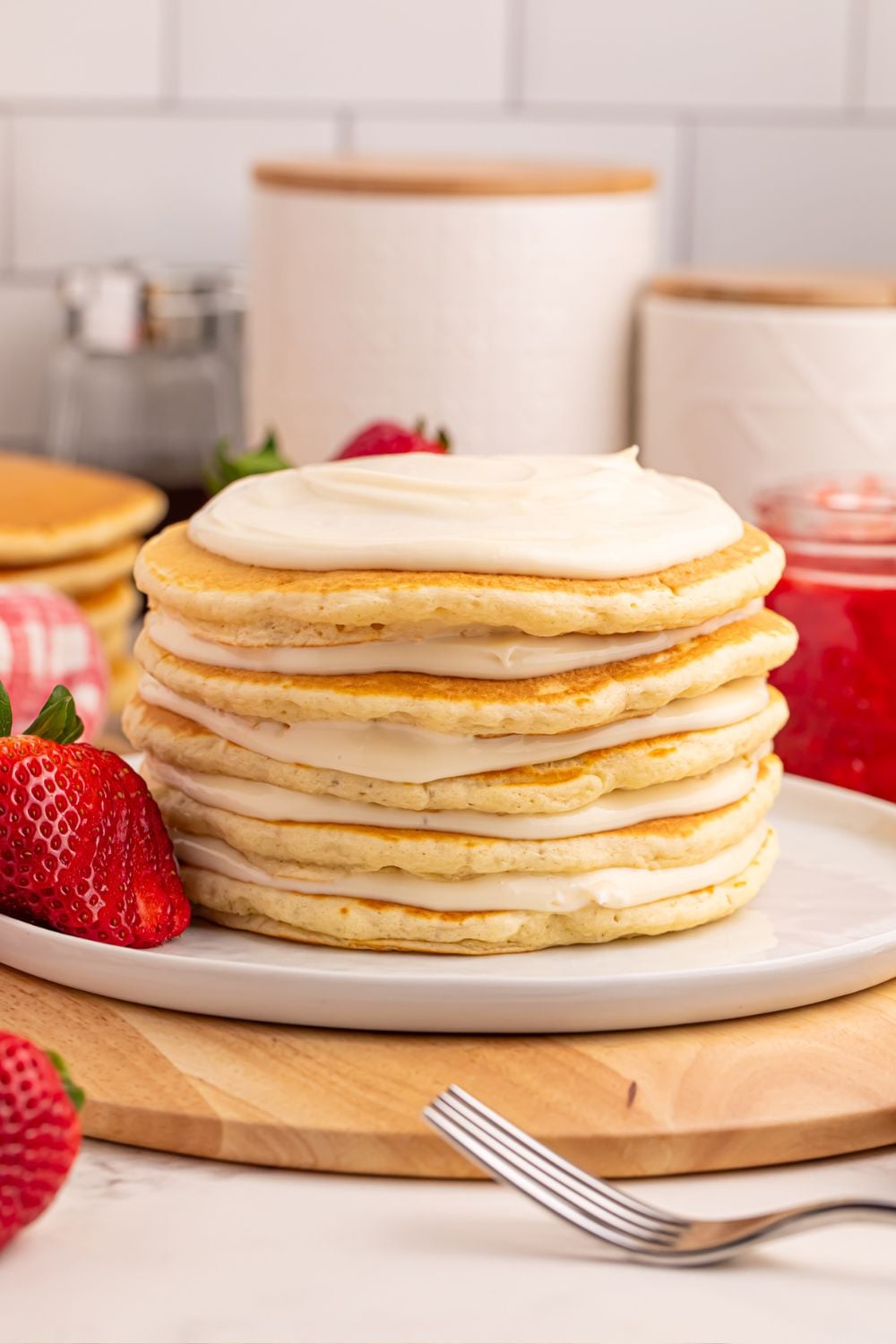 cheesecake mixture spread on top of pancakes stacked on a plate for these Strawberry Cheesecake Pancakes