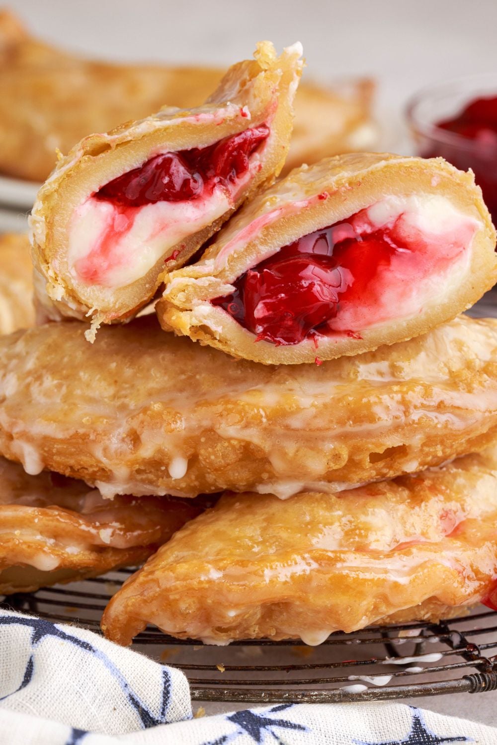 Cherry Cheesecake Hand Pies on table with one sliced in half sitting on top of the stack