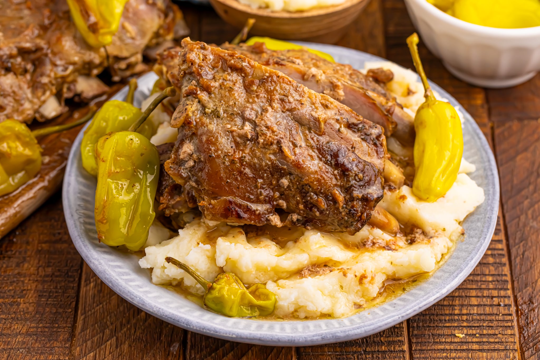Slow Cooker Mississippi Ribs on a white plate smothered in gravy sitting on top of mashed potatoes