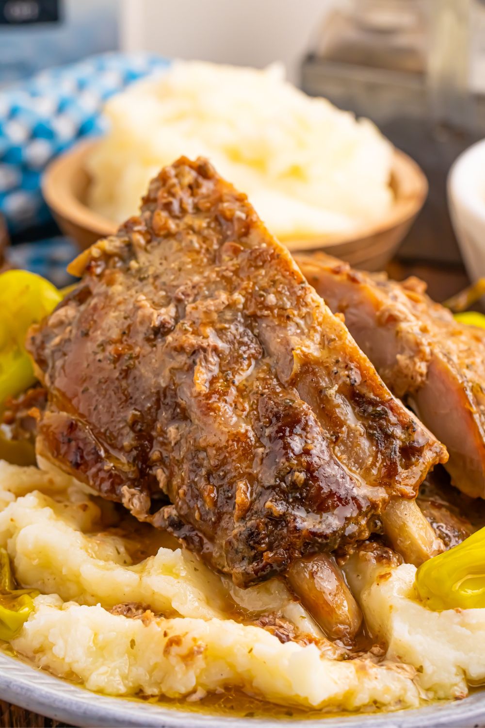 Mississippi ribs on top of a bed of potatoes and peppercini peppers on plate