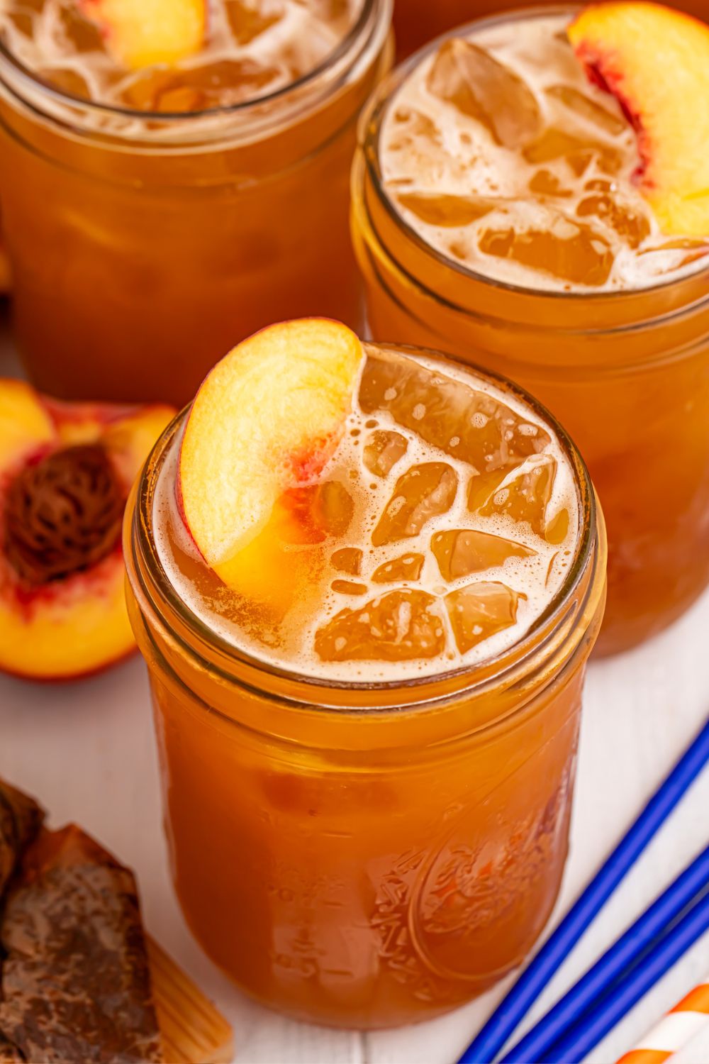 Peach Sweet Tea in mason jars with fresh peach slices in each glass sitting on top of the ice