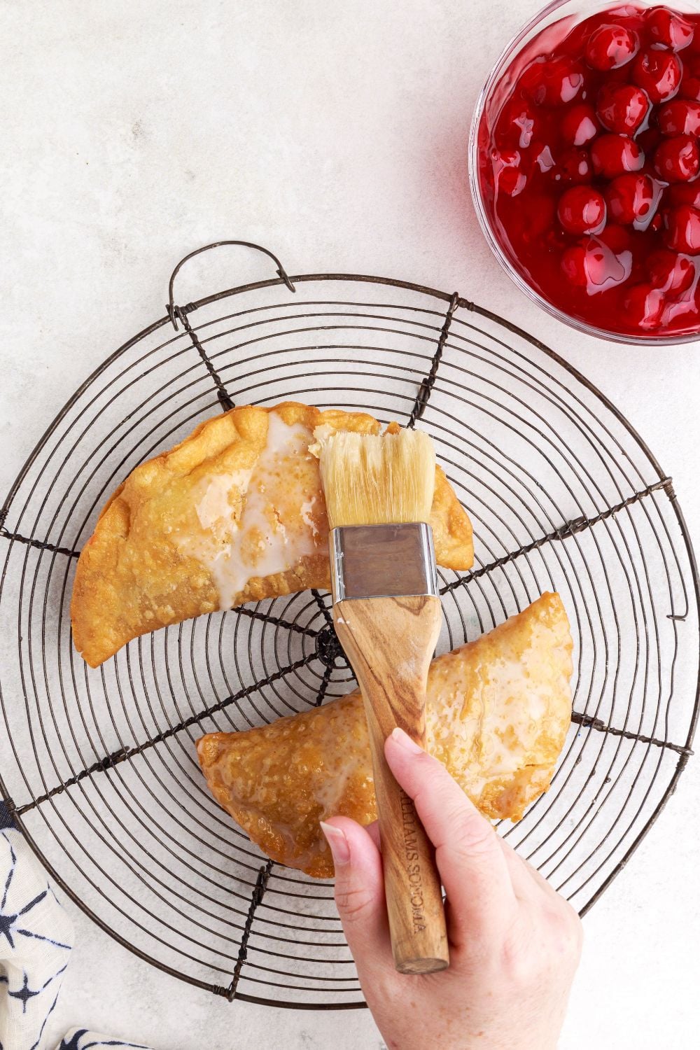brushing glaze onto the cooked Cherry Cheesecake Hand Pies
