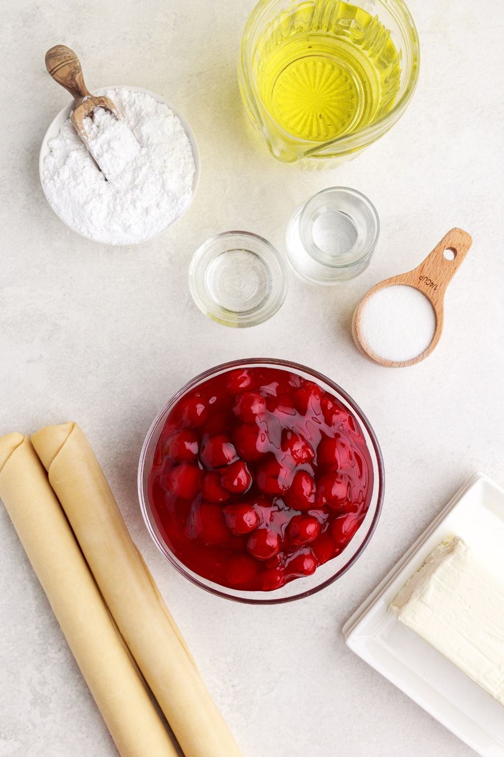 ingredients for Cherry Cheesecake Hand Pies in single serve containers on table to showcase each of the ingredients
