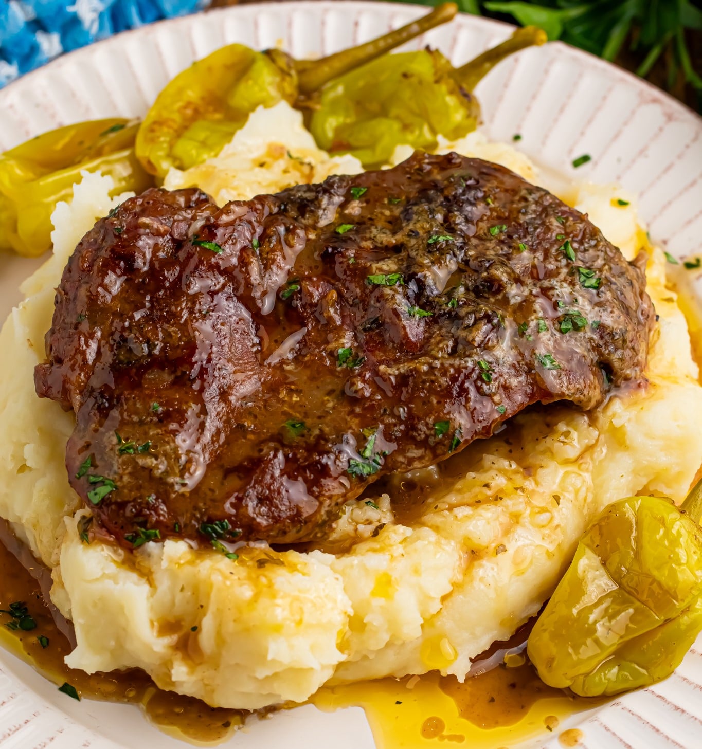 Up close shot of the Slow Cooker Mississippi Ribeye Steaks on a white plate, on top of fluffy mashed potatoes with gravy