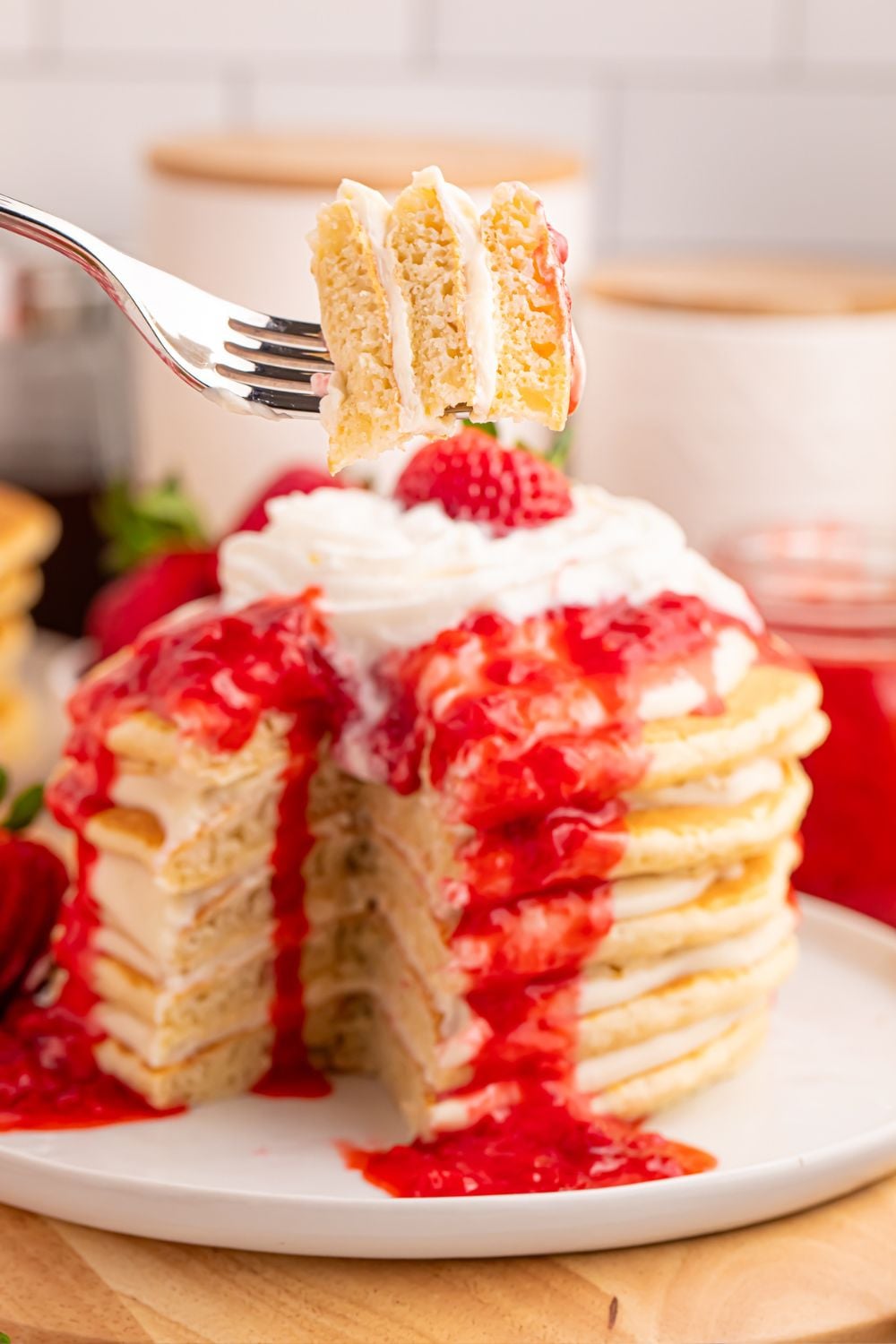 Strawberry Cheesecake Pancakes on a plate with a fork full of pancakes in front of plate