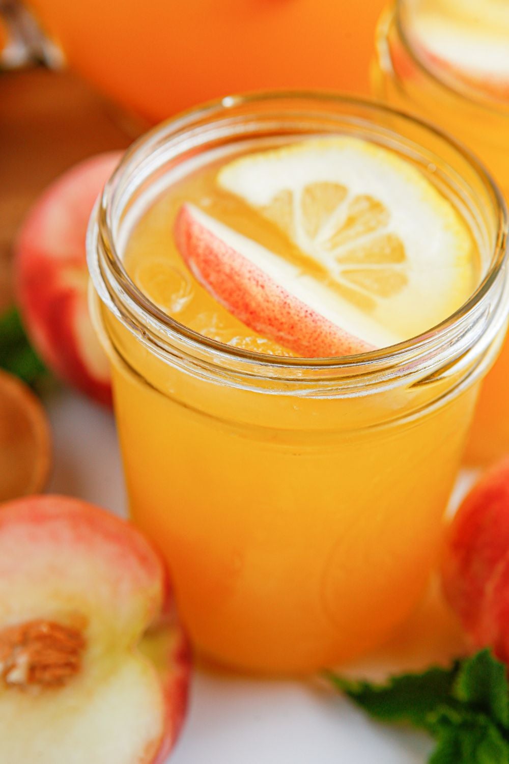 Peach Lemonade in glasses with fresh fruit all around it