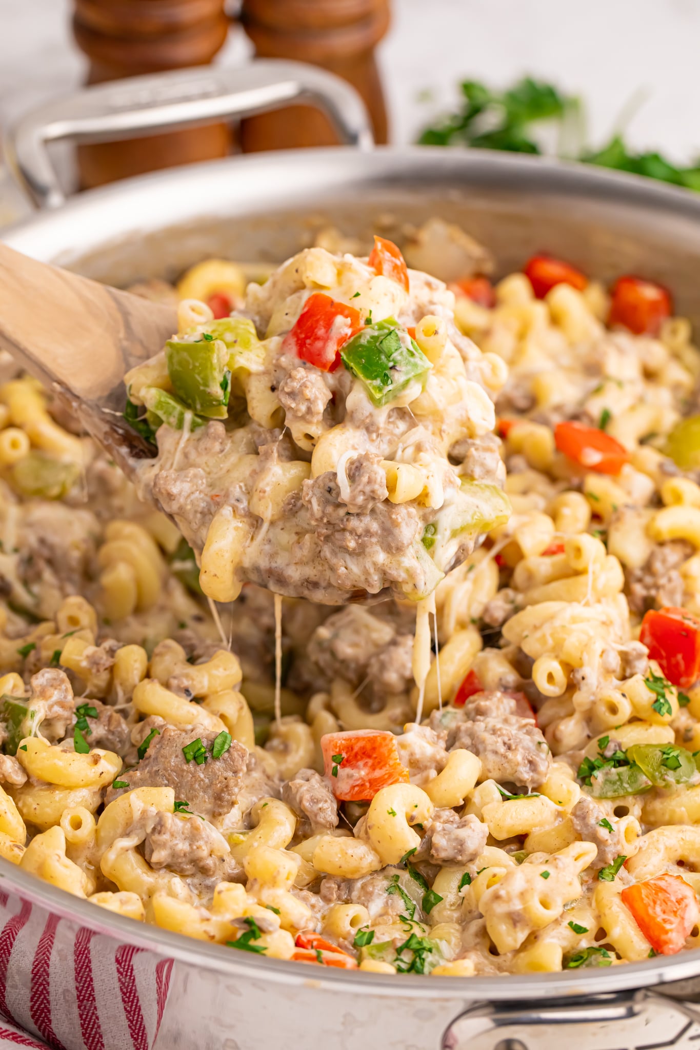 Philly Cheesesteak Pasta in a skillet on table with spoon lifting up a large bite
