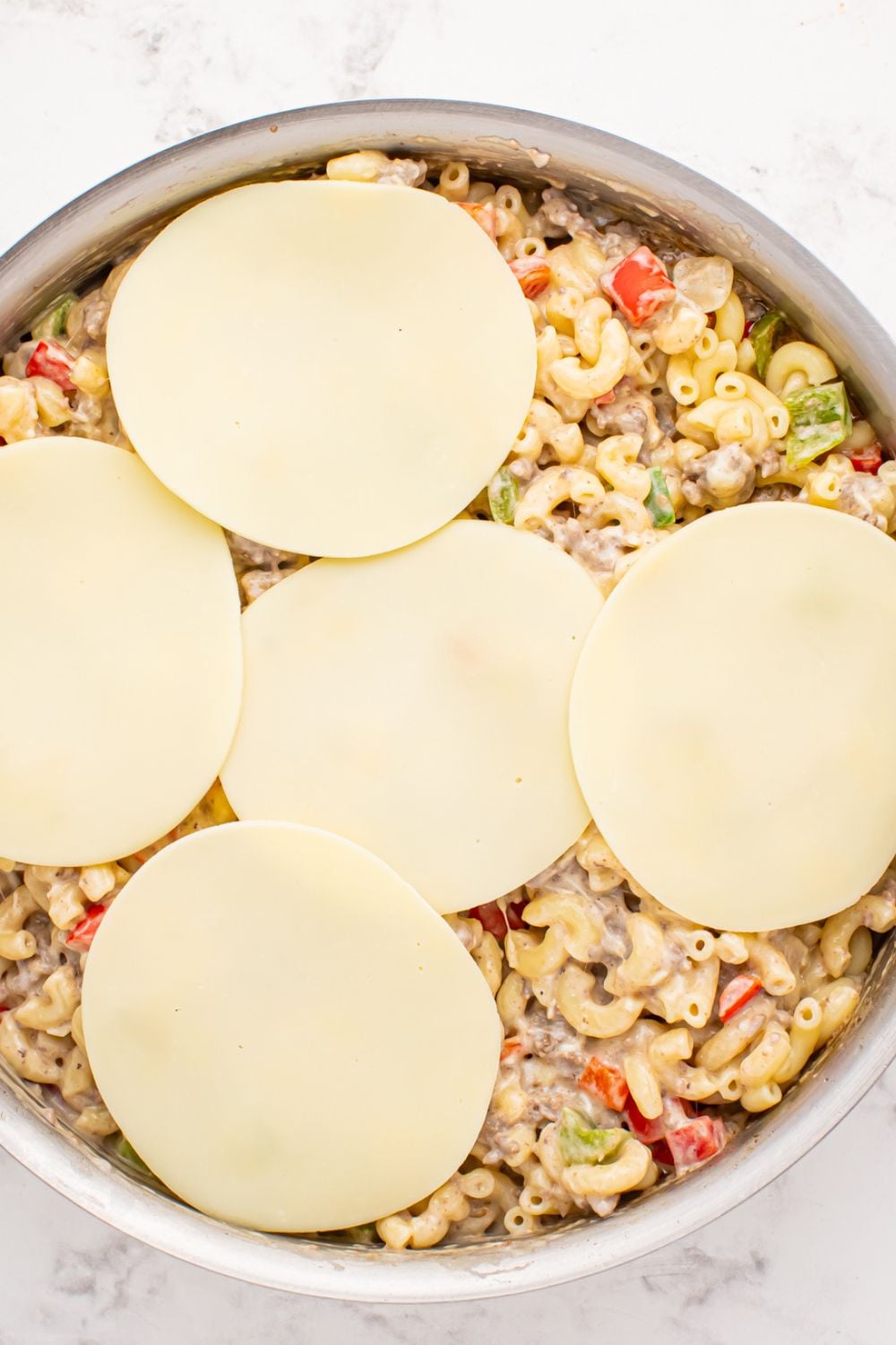 provolone cheese slices on top of the Philly Cheesesteak Pasta mixture in skillet