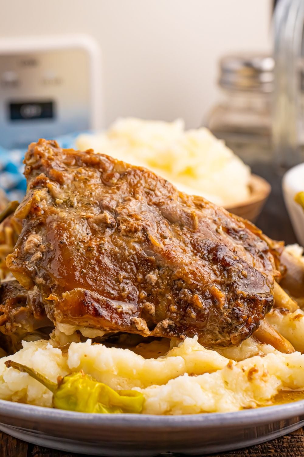 plate of baby back ribs, mashed potatoes and peppers with food in background blurred out