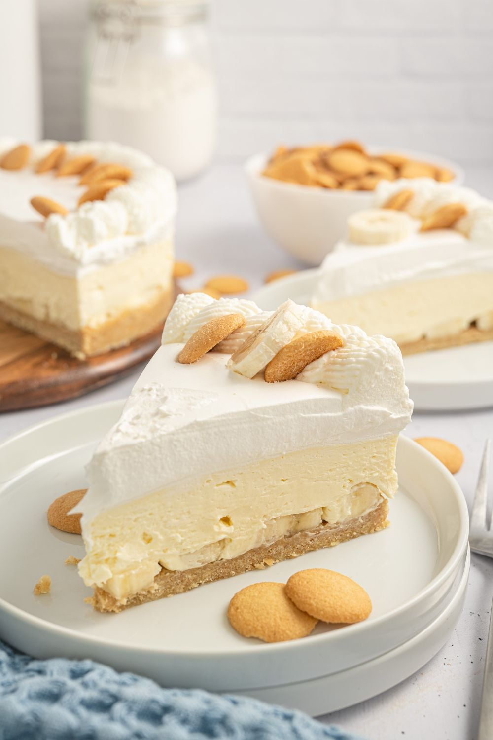 banana pudding cheesecake slices on plates with vanilla wafer cookies scattered on plates