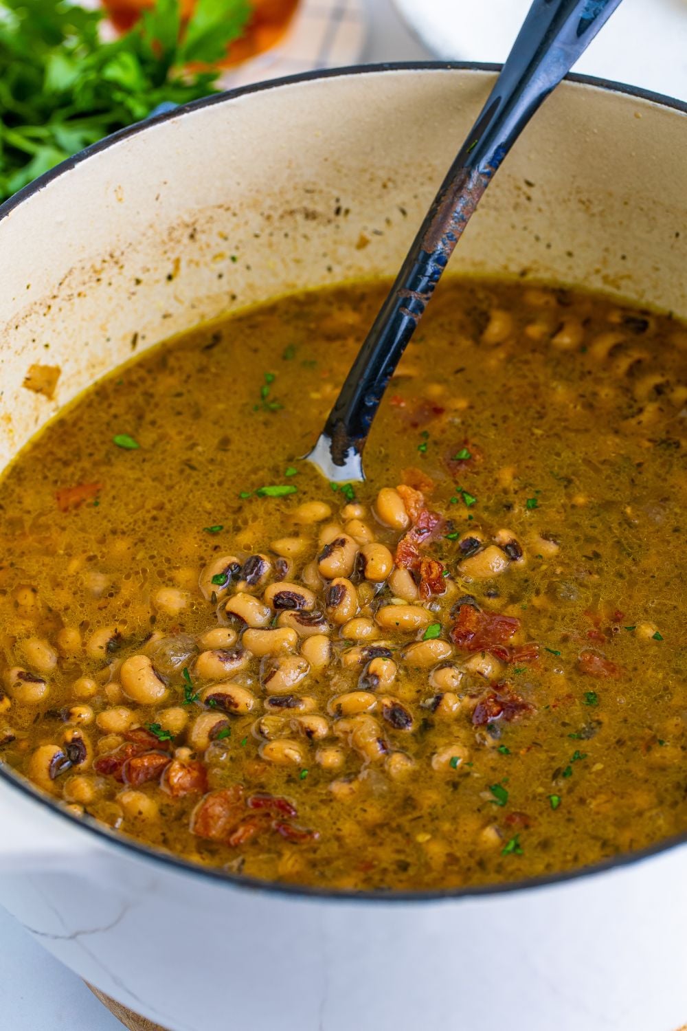 black eyed peas in a pot with a metal spoon showing the peas 