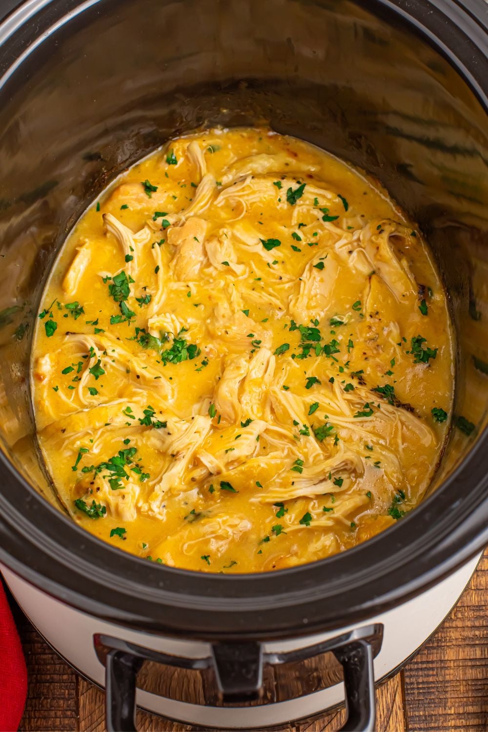 overhead look of crockpot with chicken and gravy in the pot with parsley sprinkled on top