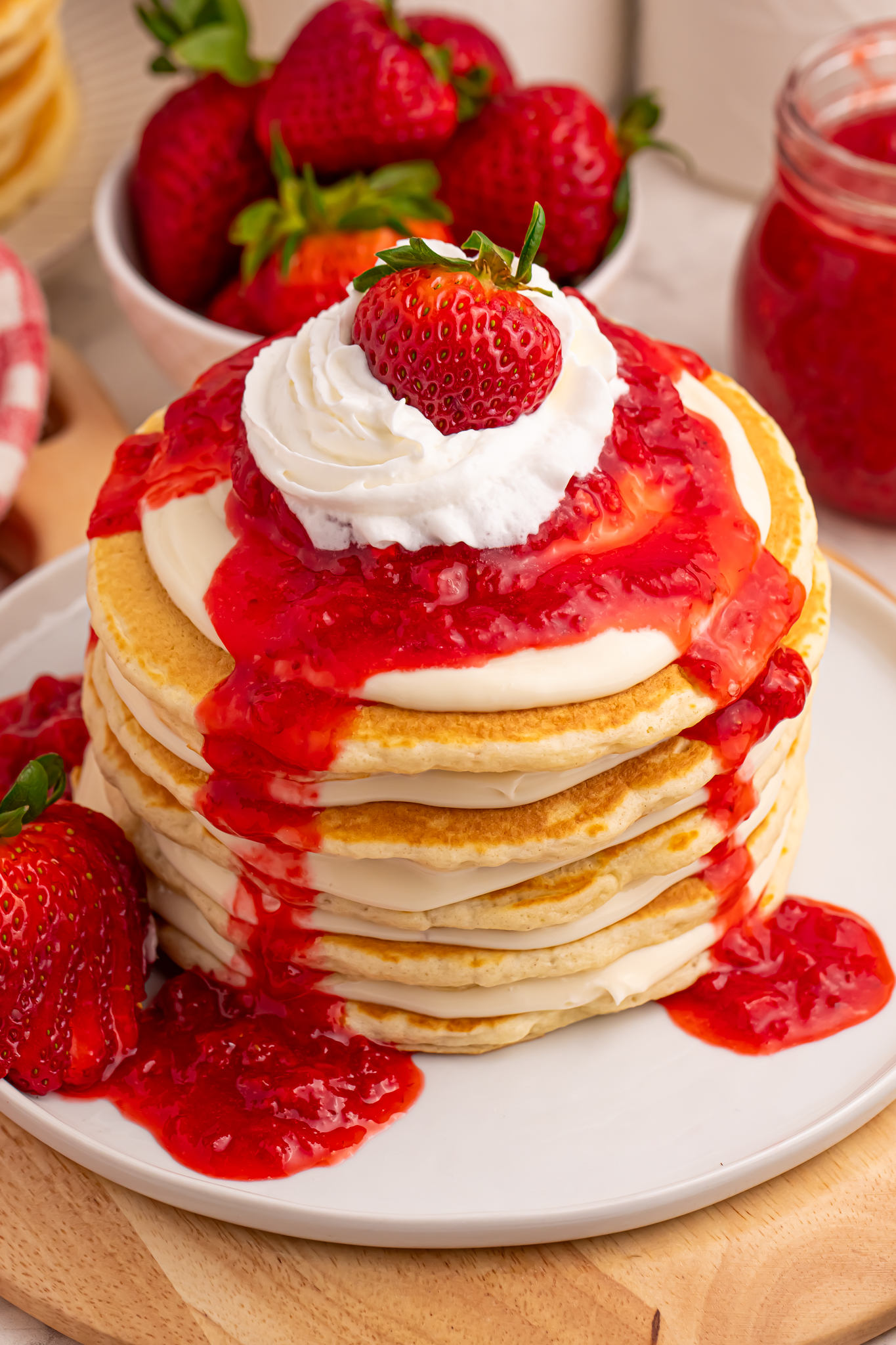 Strawberry Cheesecake Pancakes on a white plate with strawberry sauce drizzled overtop
