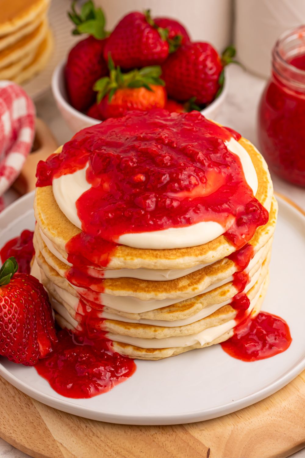 stack of Strawberry Cheesecake Pancakes on a plate with strawberry sauce on top
