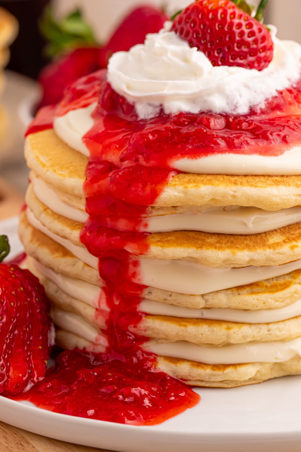 Strawberry Cheesecake Pancakes stacked on a plate showing the layers of cheesecake spread and pancakes closer