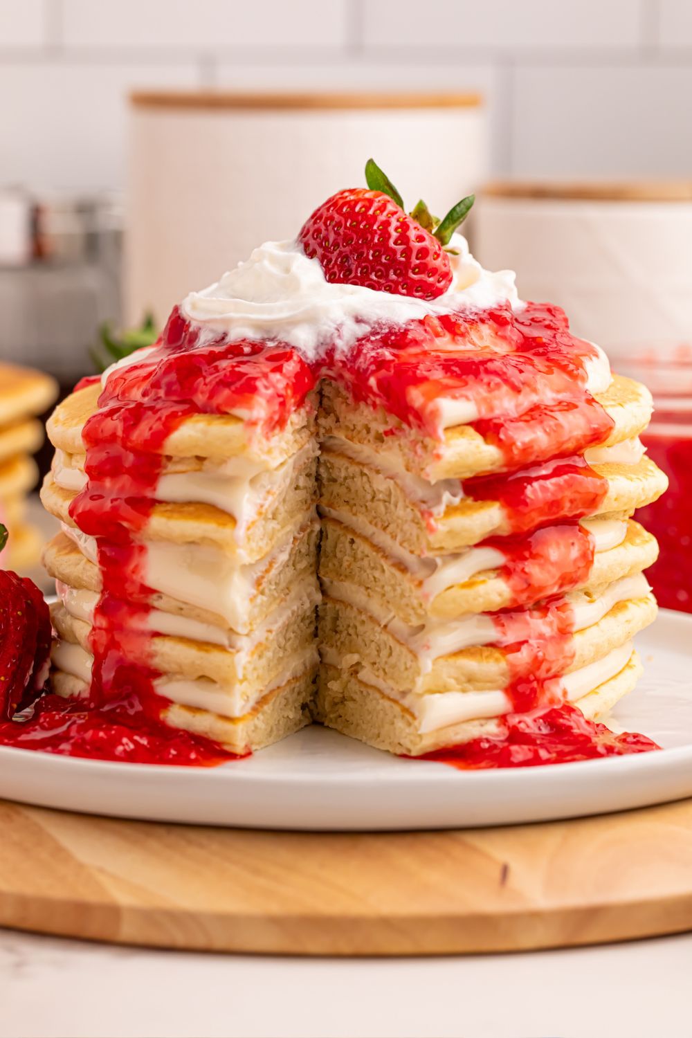 Strawberry Cheesecake Pancakes stacked on plate with a cut in them to show the cheesecake layers