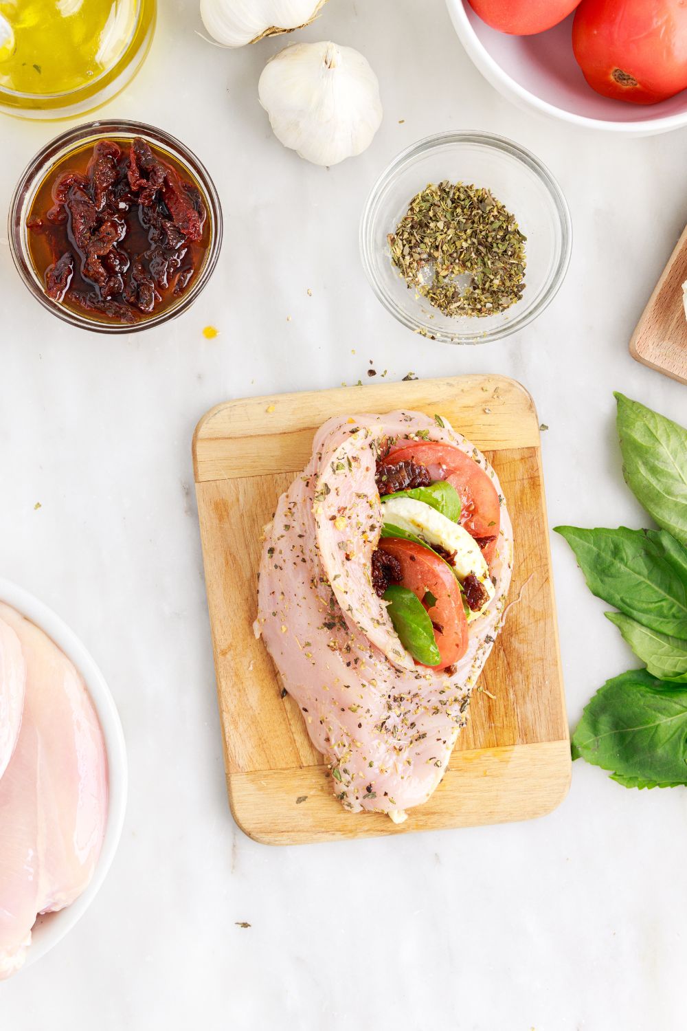 stuffed raw chicken on cutting board for the Caprese Stuffed Chicken recipe 