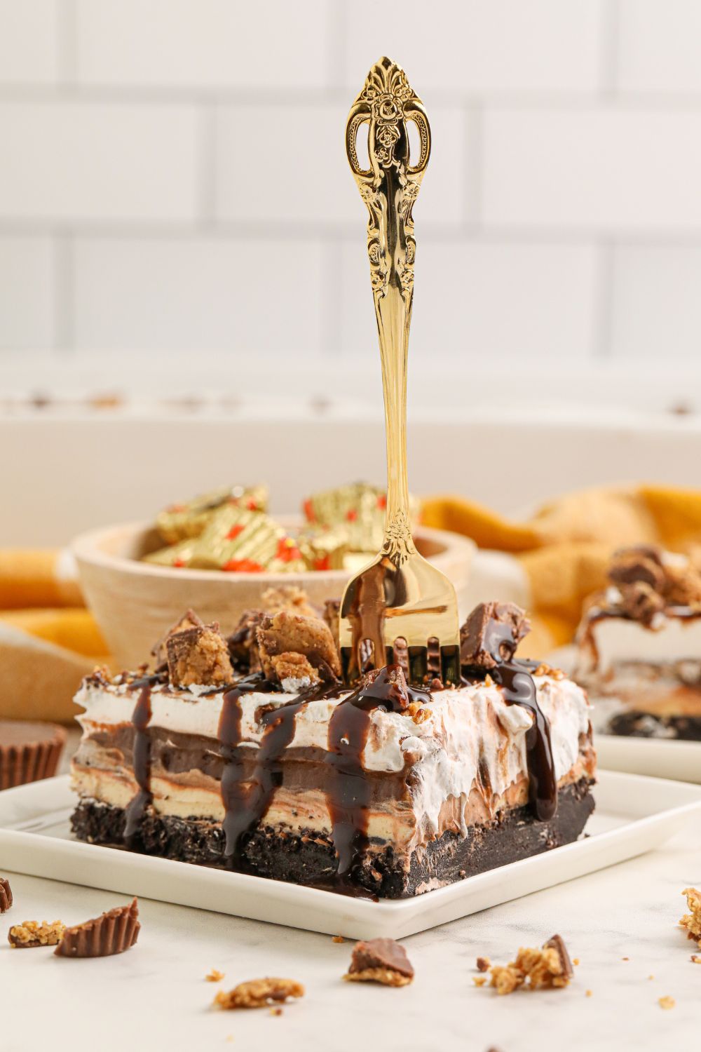Reeses Lasagna slice on table with a fork in it and a bowl of Reese's behind it