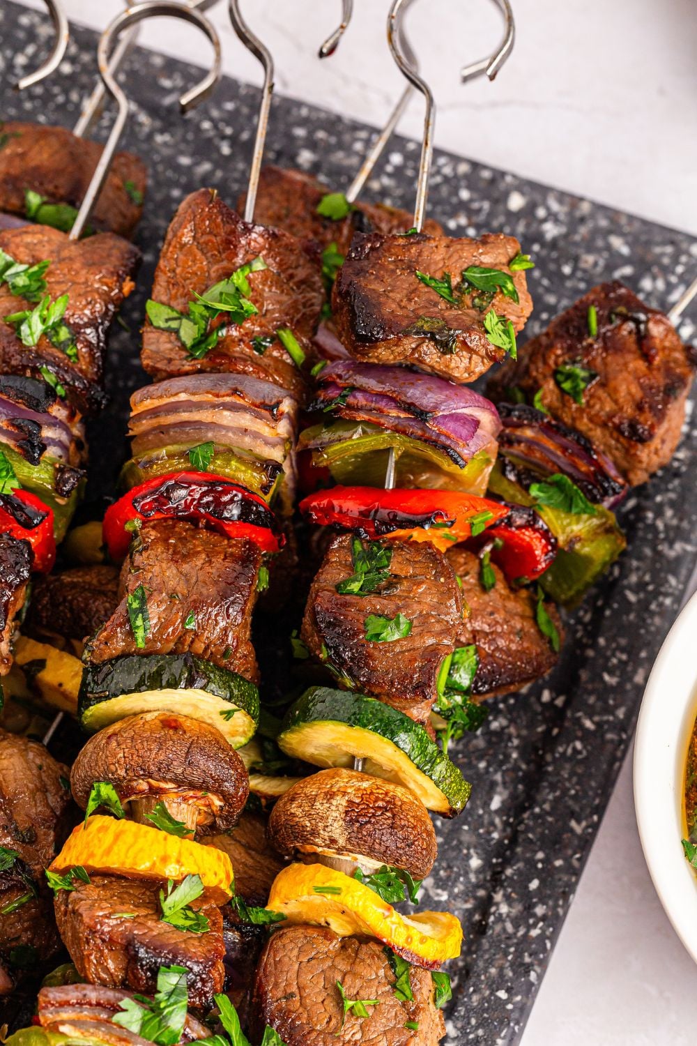 cooked beef and vegetable kabobs sitting on a tray with metal skewers in them