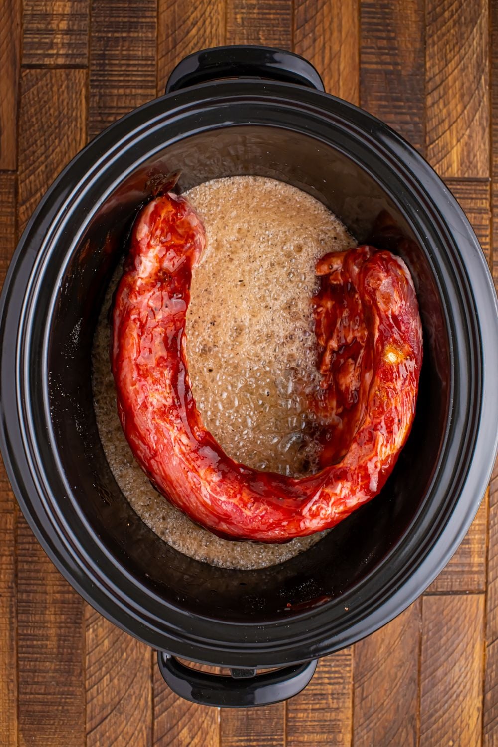 Slow Cooker Coca Cola Ribs in slow cooker with coke poured in and seeing the bubbles 