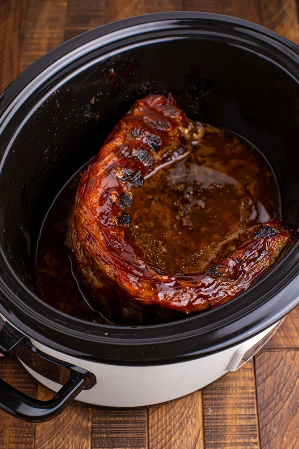 slow cooker with cooked Coke ribs inside it