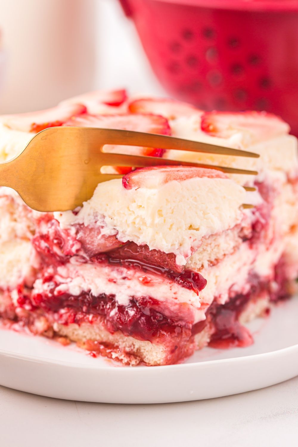 gold fork slicing into a piece of Strawberry Tiramisu