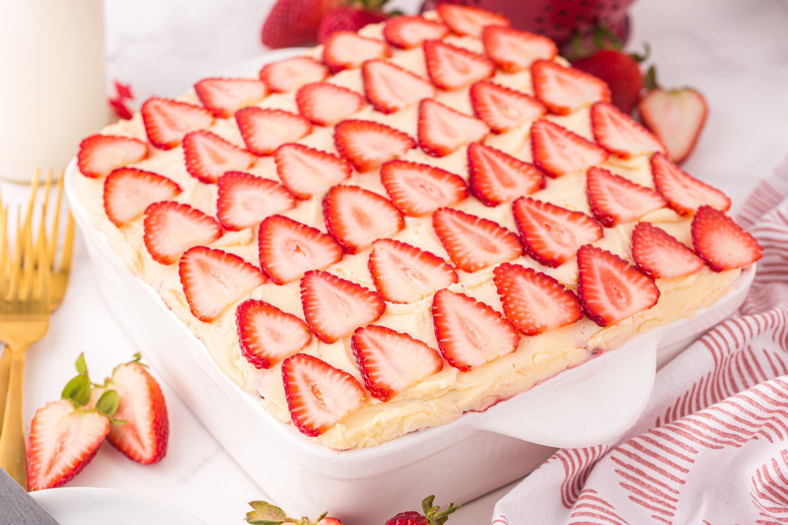 Strawberry Tiramisu in a pan on table with a towel behind it