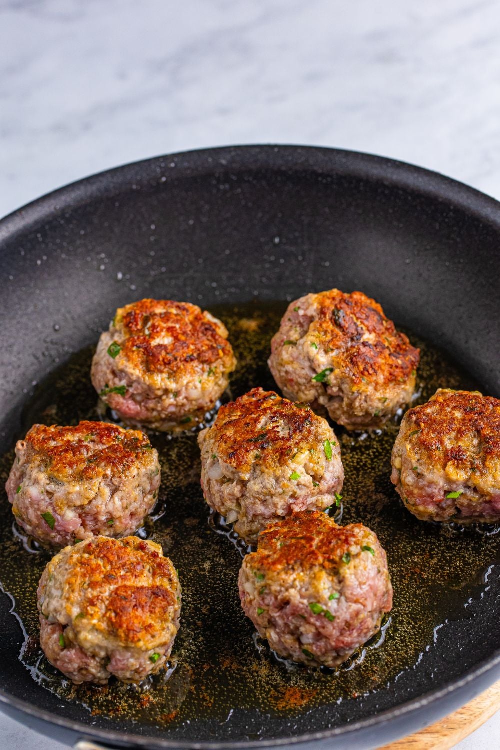 Classic Italian Meatballs being seared in a skillet 