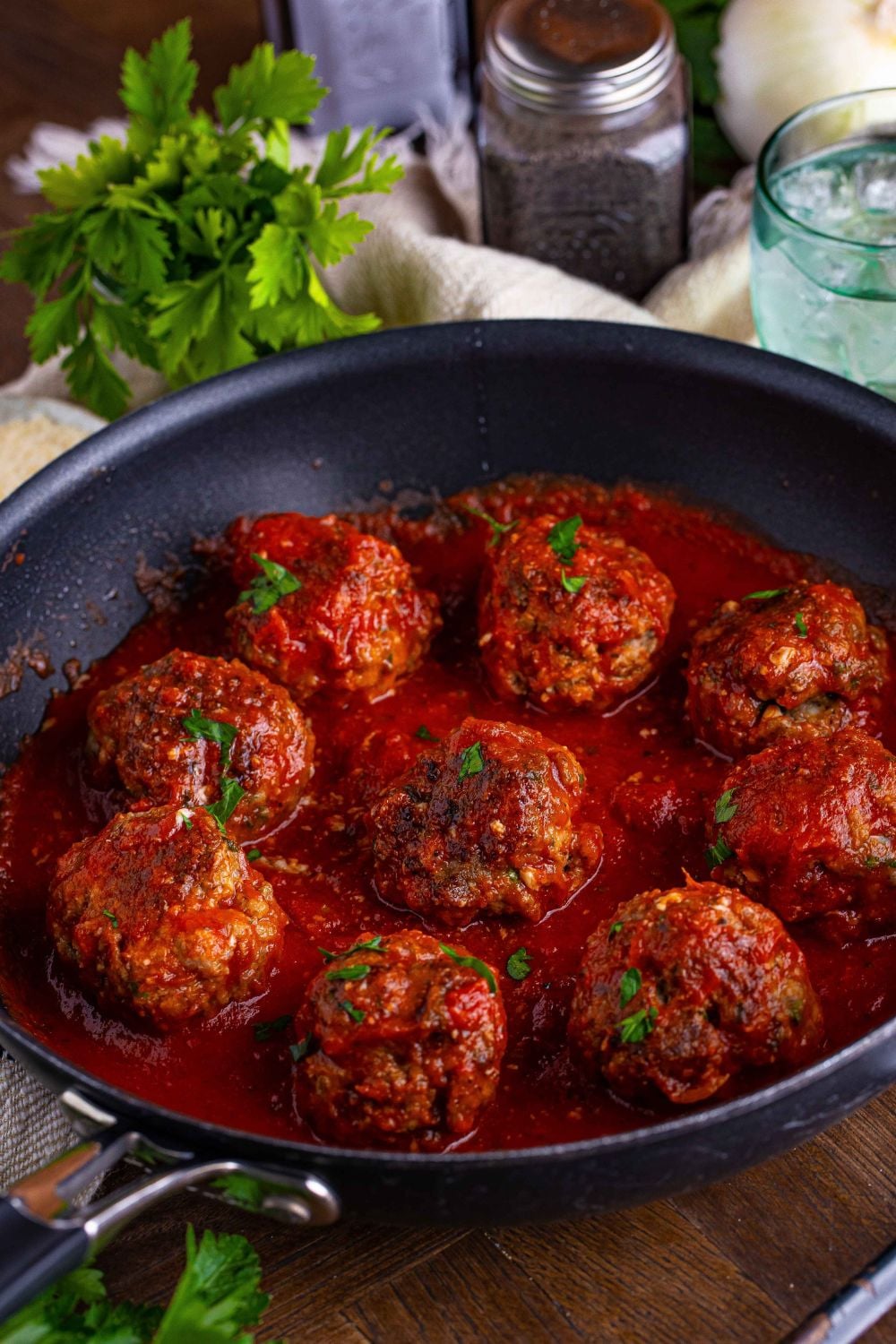 Italian Meatballs in a pan with parsley and salt and pepper in the background 
