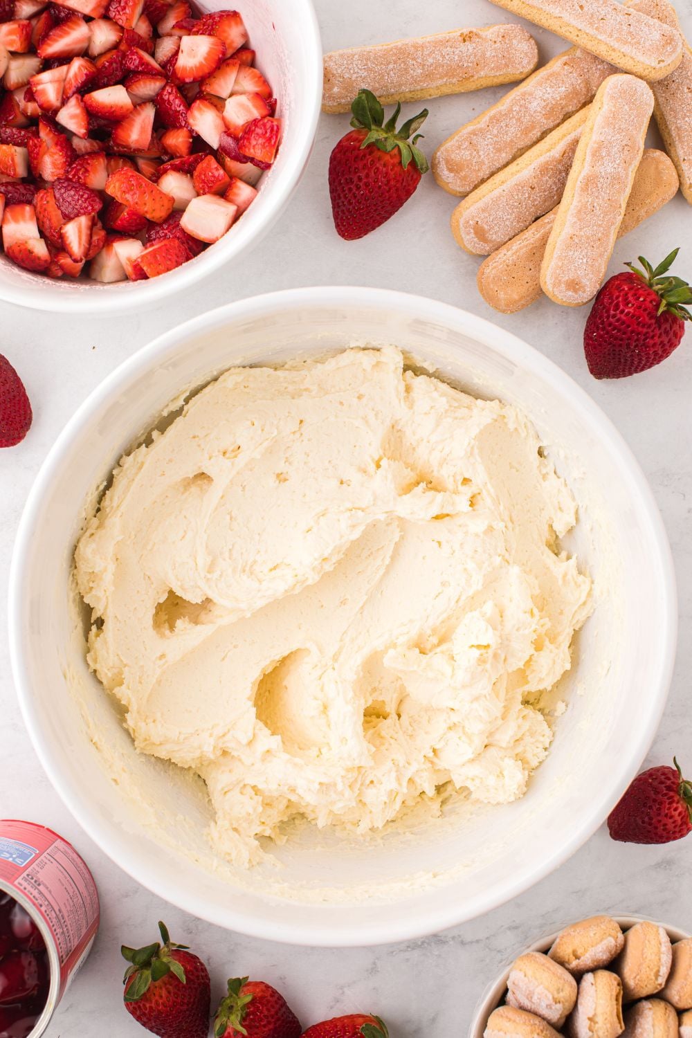 mascarpone filling on table in a bowl with ladyfingers and berries in bowls