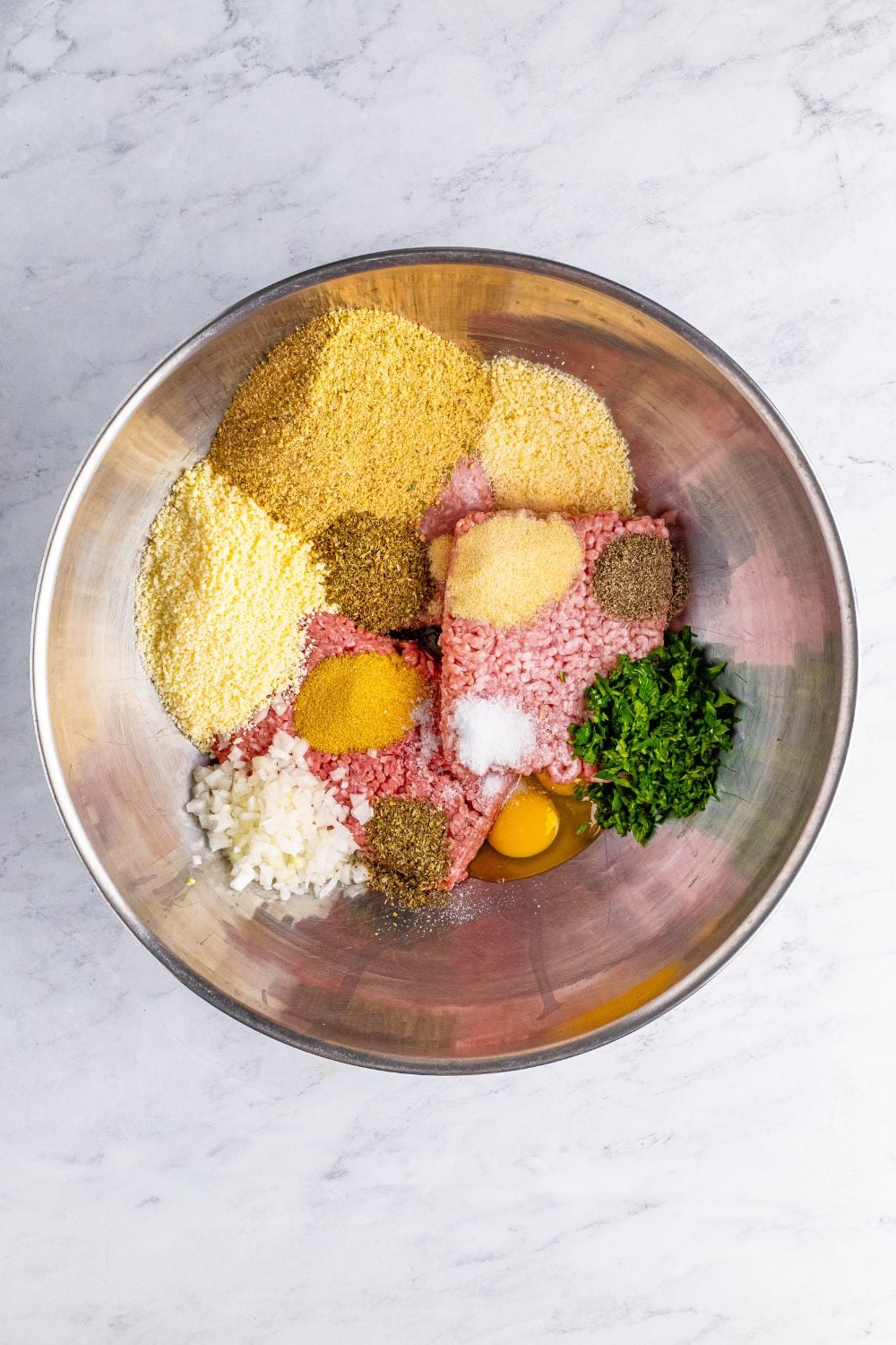 ingredients for the meatballs in a metal bowl on table 