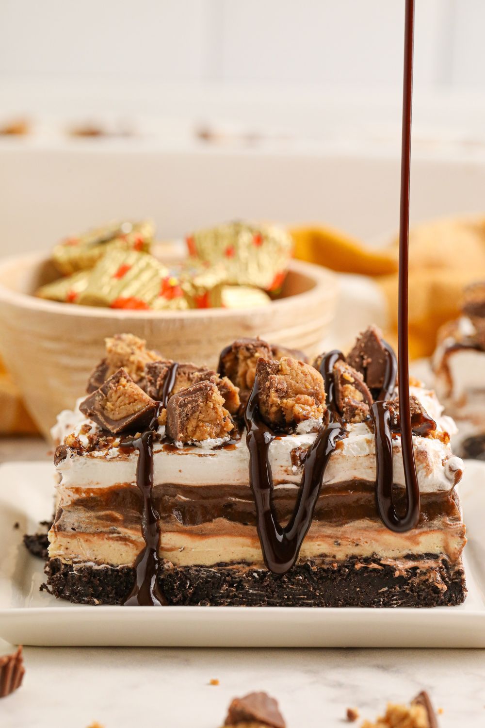 chocolate sauce being drizzled on top of Reeses Lasagna on plate