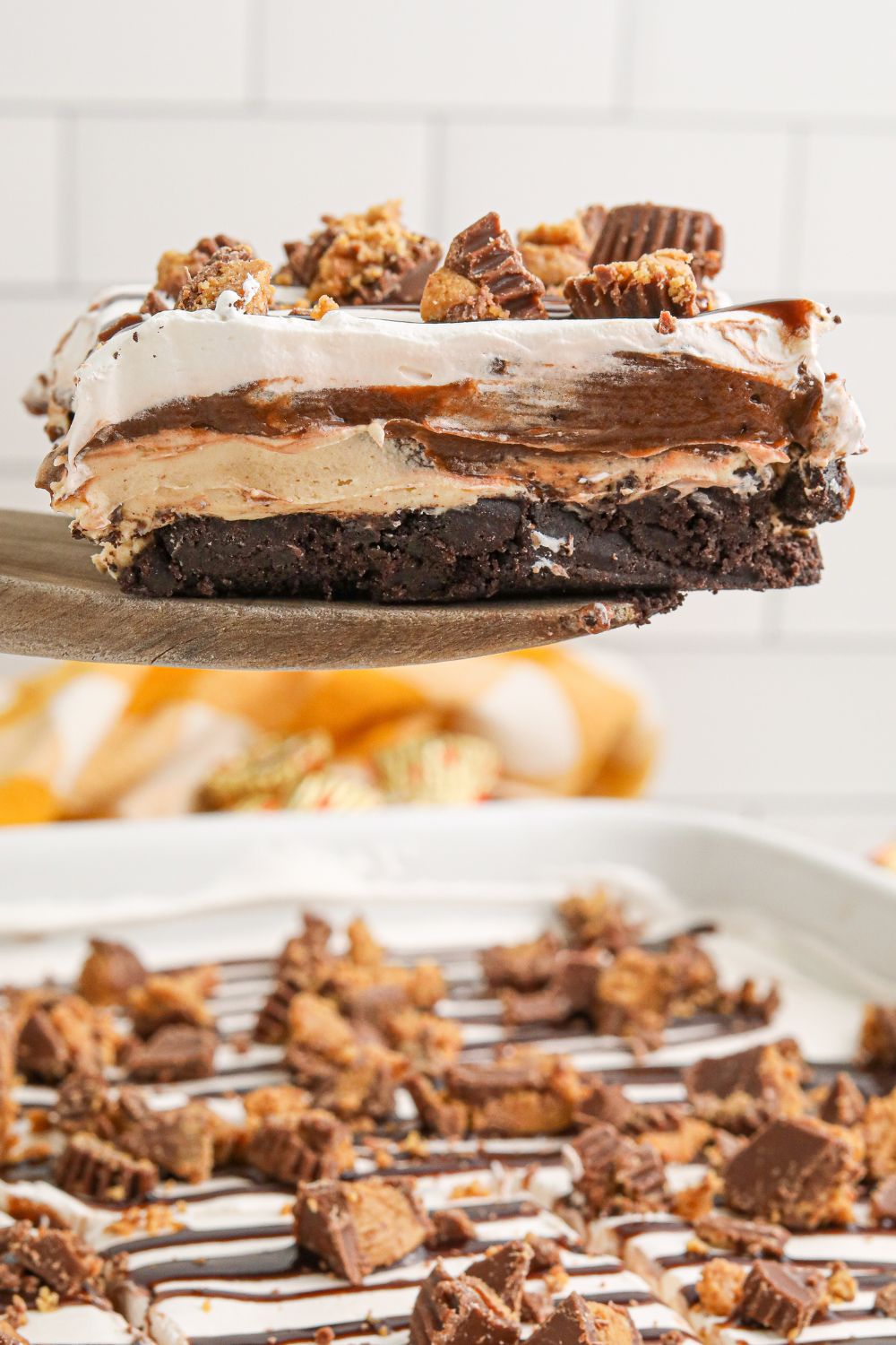 Reeses Lasagna in a pan with one slice being lifted out of pan with a spatula