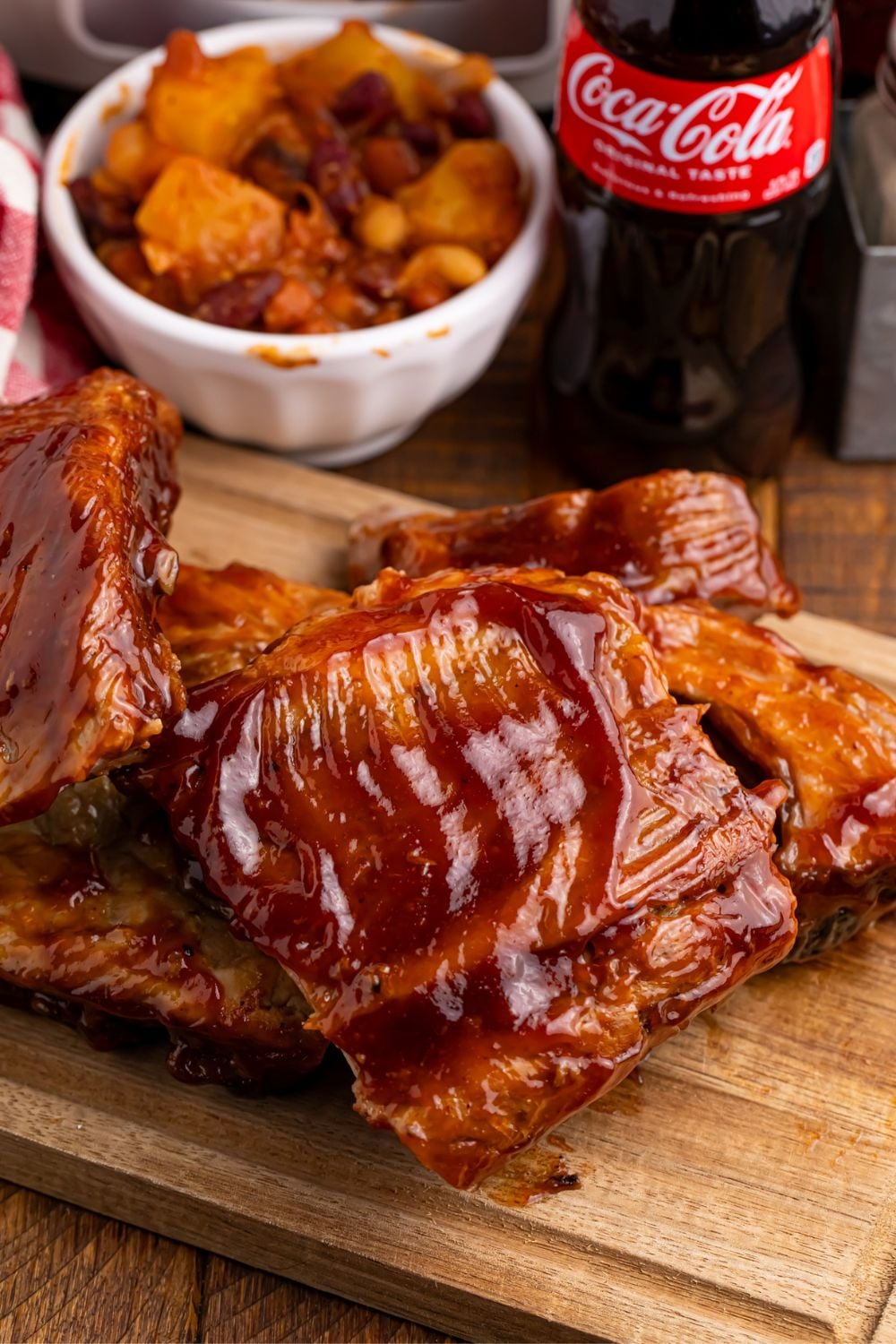 ribs smothered in bbq sauce stacked on top of each other on a wooden cutting board 