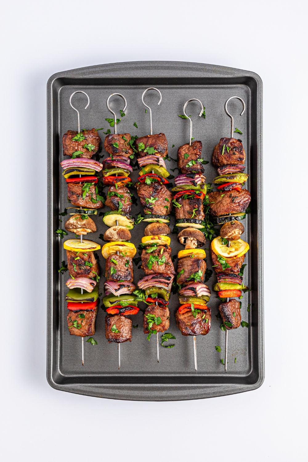 cooked Marinated Beef Kabobs on a baking sheet on table