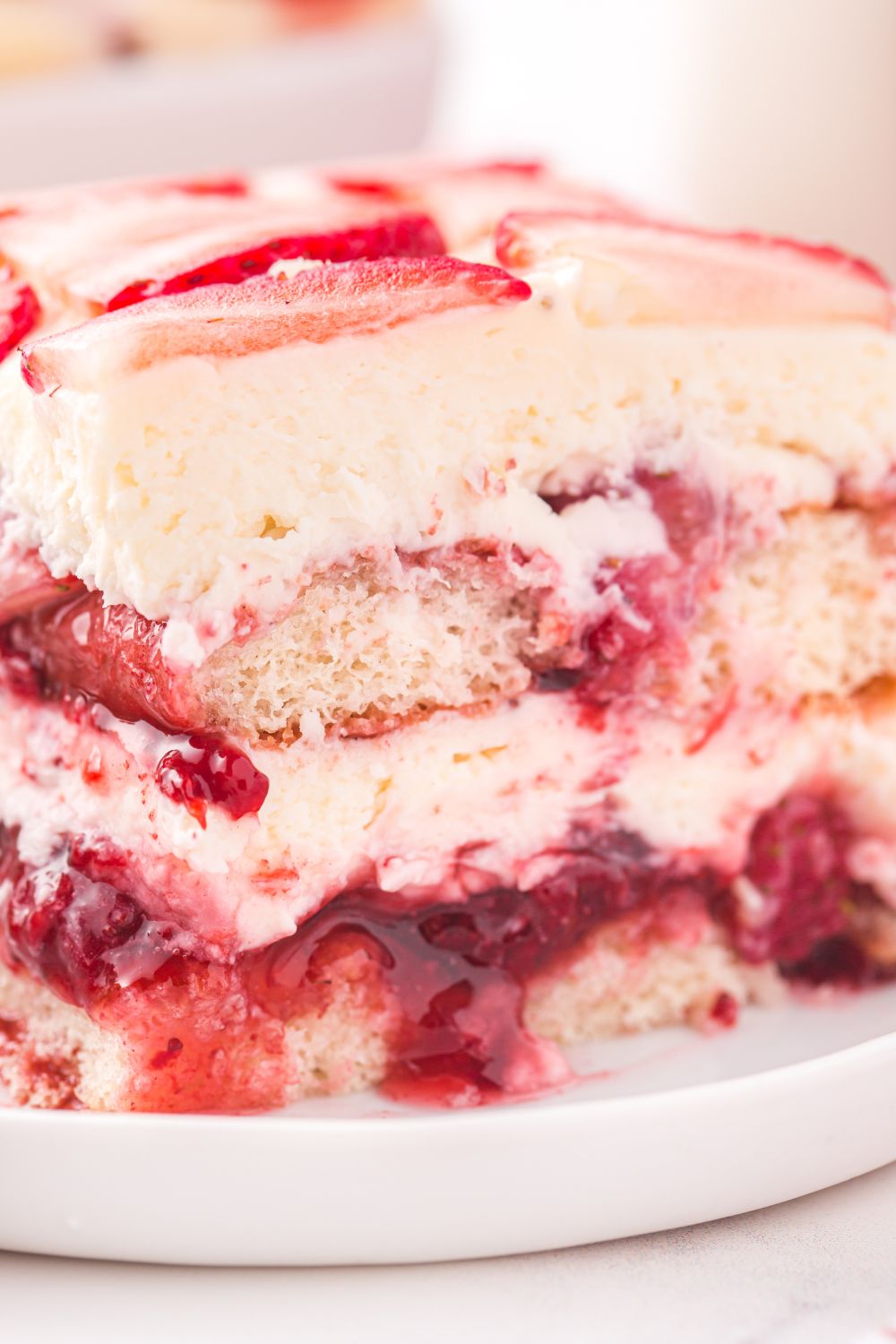 Strawberry Tiramisu sliced on a plate with a glass of milk behind it