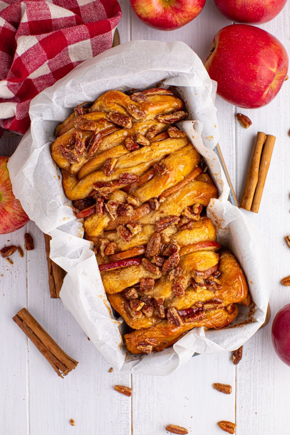 Apple Pie Pull Apart Bread in the loaf pan sitting on table with spices and apples around it on table