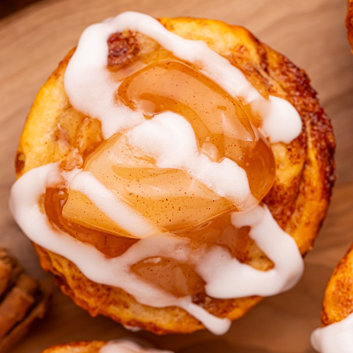 overhead shot of an apple pie cup with a drizzle of icing on top sitting on a wooden cutting board on table