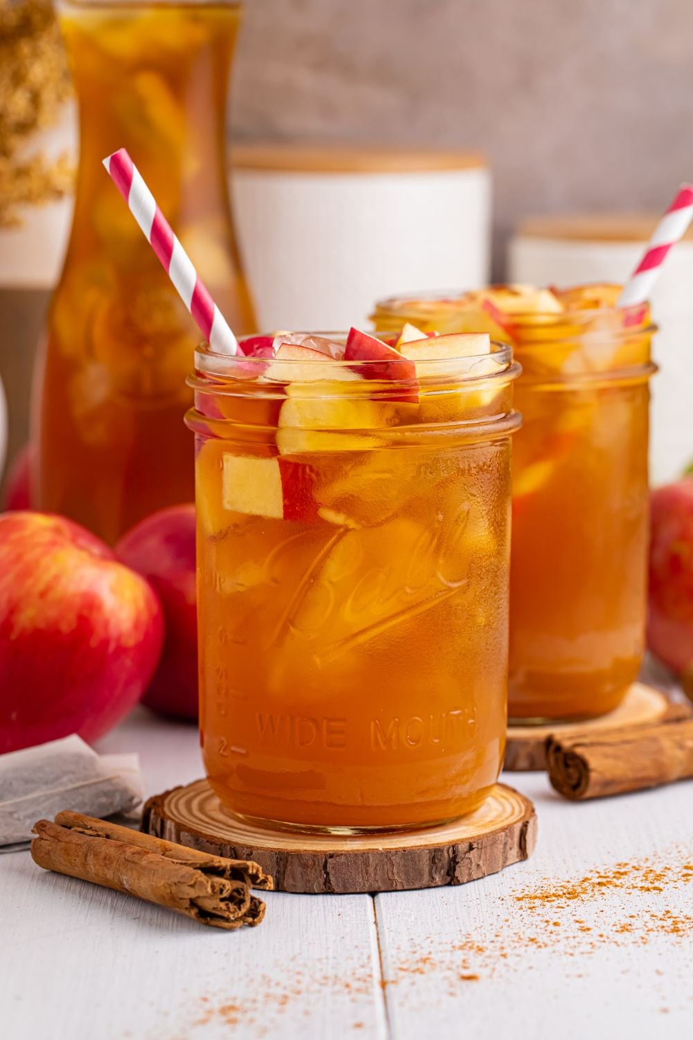 apple cider and tea in glasses on table with a sprinkle of cinnamon on table and apples