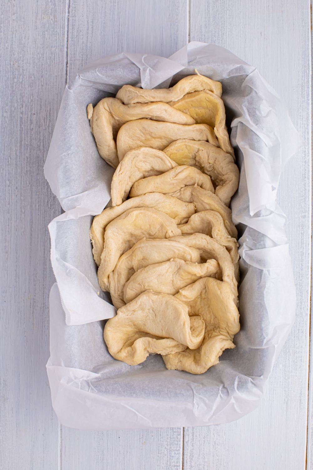 pulled apart biscuit dough in a loaf pan for making the Apple Pie Pull Apart Bread