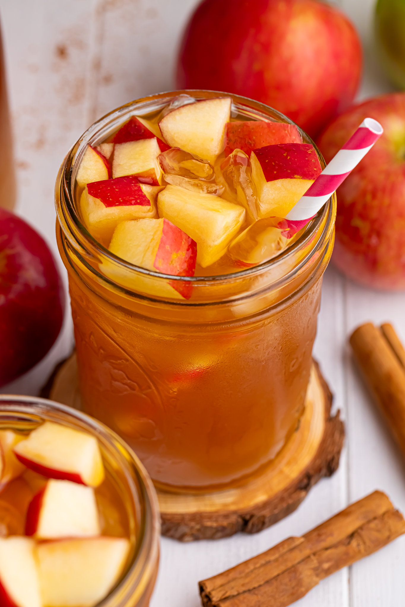 apple cider iced tea in a glass with an overhead look of glass with a straw in it and diced fresh apples with ice cubes