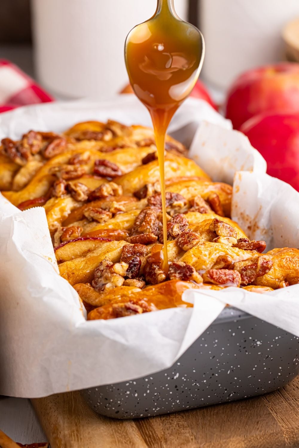 caramel sauce dripping off a spoon onto the Apple Pie Pull Apart Bread in a pan on the table