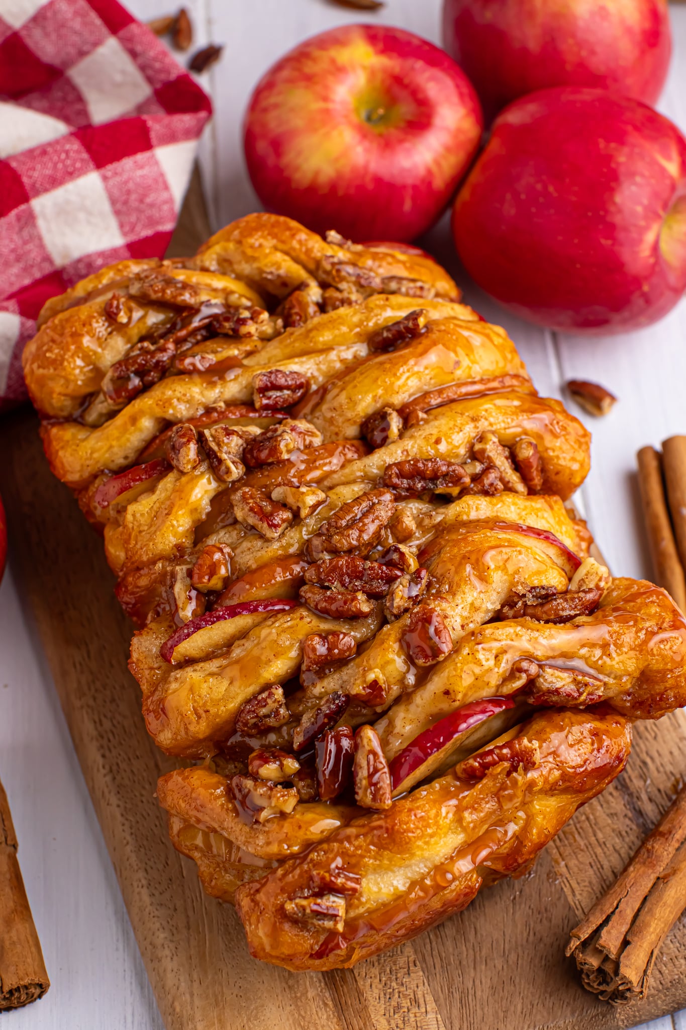 Apple Pie Pull Apart Bread in a pan sitting on table topped with nuts and caramel sauce