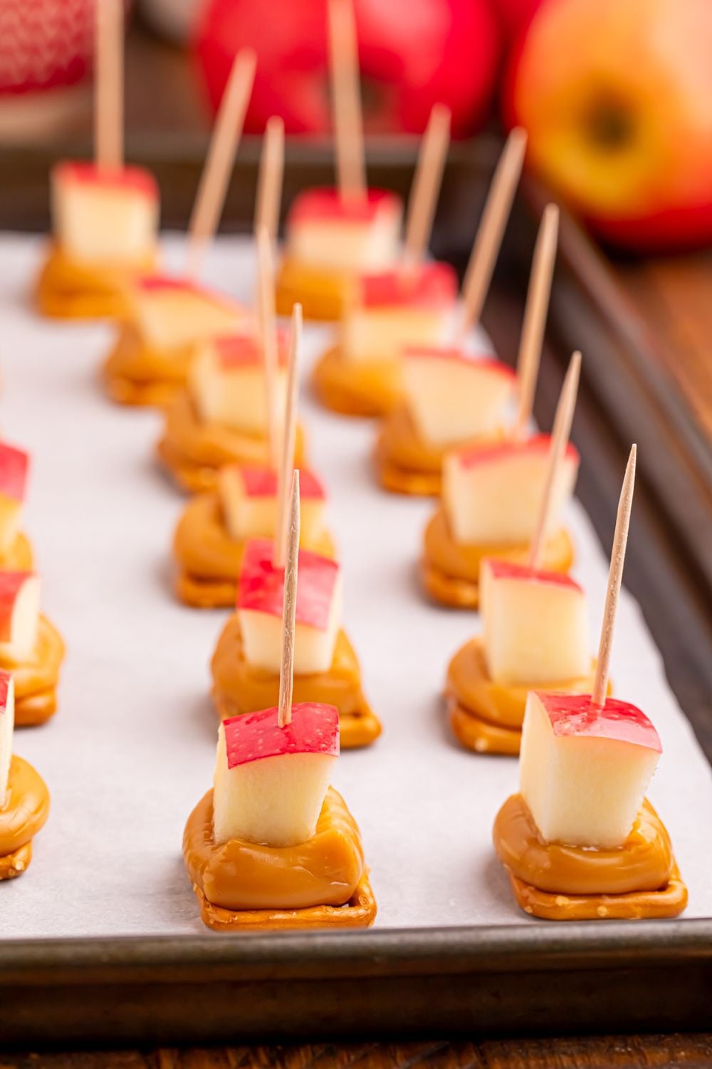 caramel apple bites with pretzels spread out on a cookie tray on table