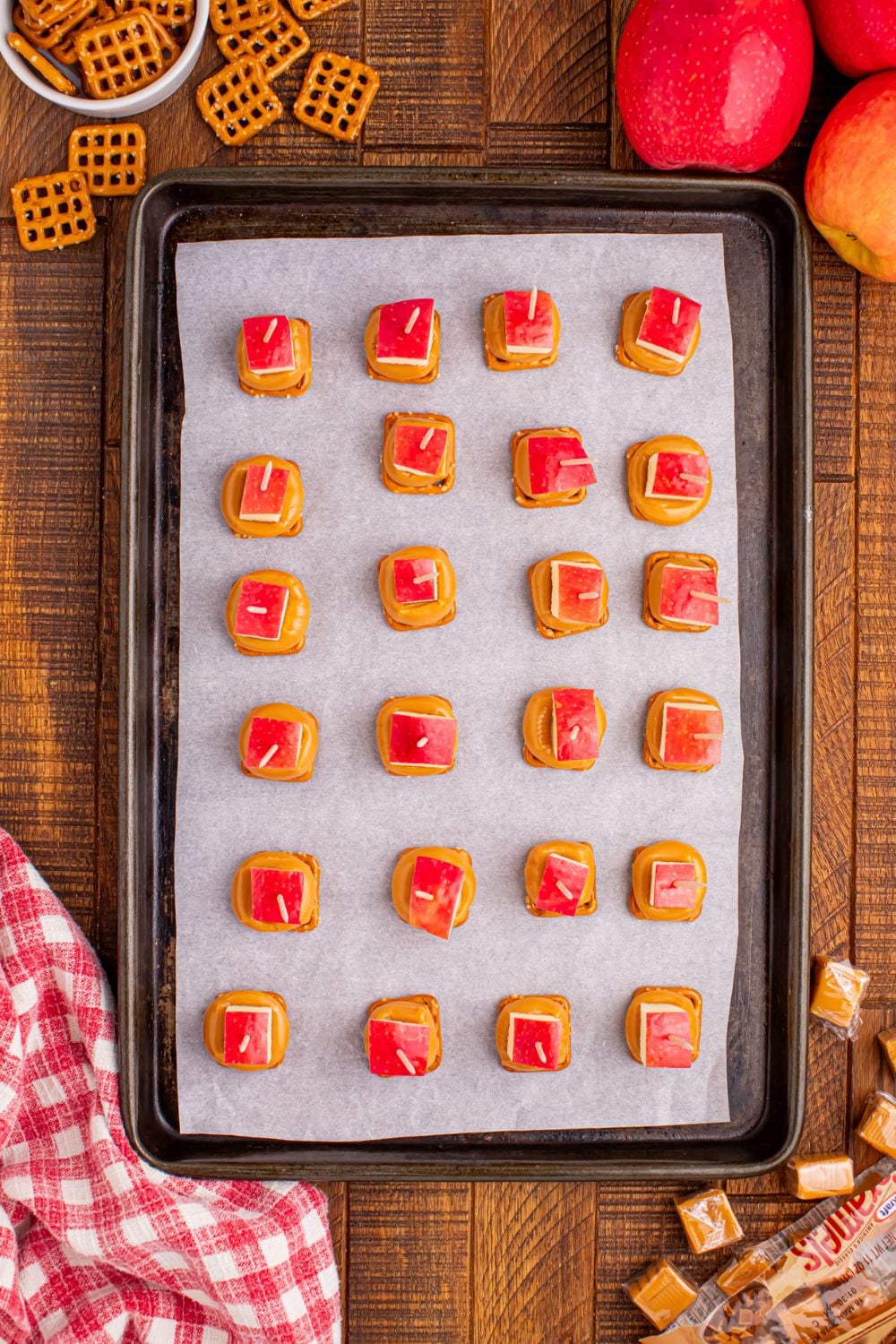 caramel apple bites on a baking sheet that are assembled and topped with pretzels