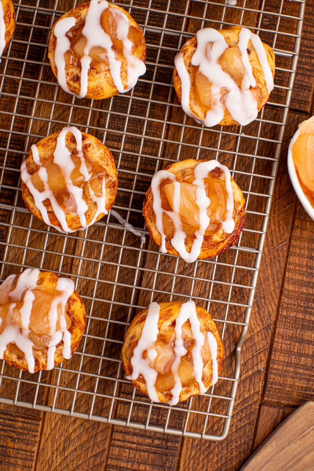 apple cinnamon cups on table on a wire cooling rack with a bowl of pie filling on the side